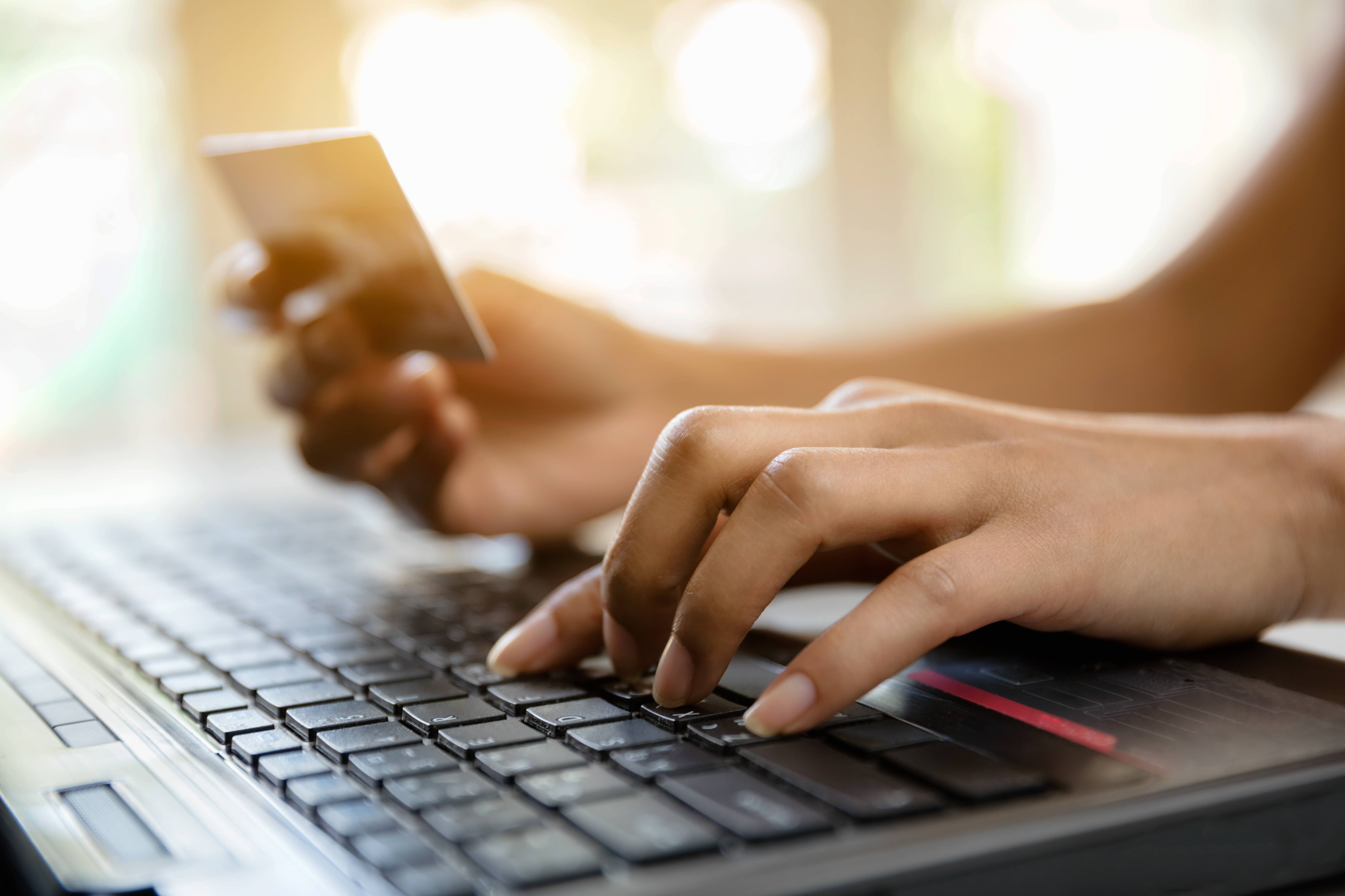 Imagen de manos sosteniendo una tarjeta de crédito y usando una computadora portátil para representar compras / comercio electrónico en línea.