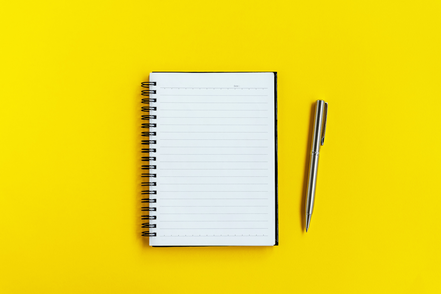 Bloc de notas y bolígrafo sobre fondo amarillo