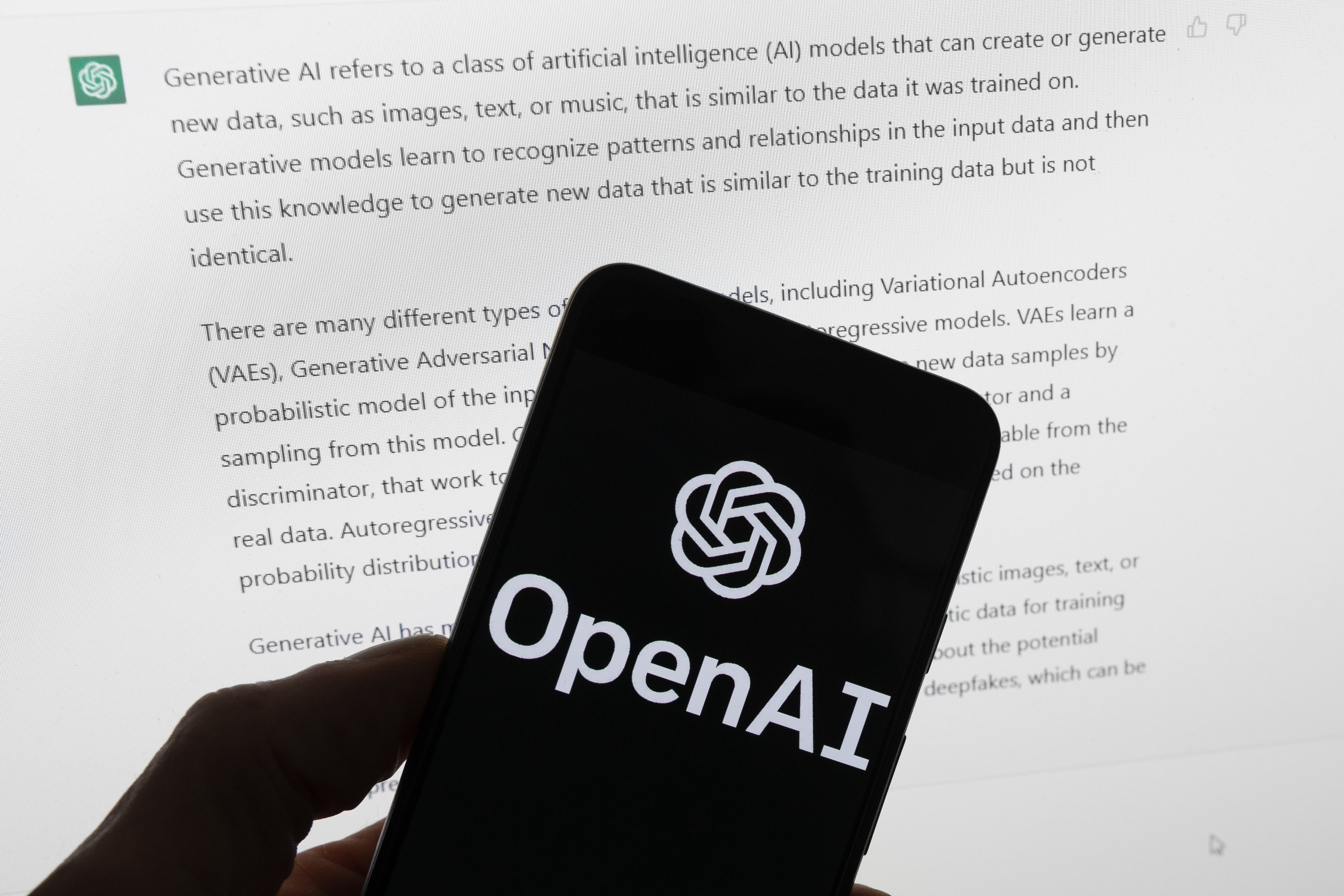 El logo de OpenAI en un celular frente a una pantalla de computadora que exhibe un texto generado por ChatGPT (AP Foto/Michael Dwyer, Archivo)